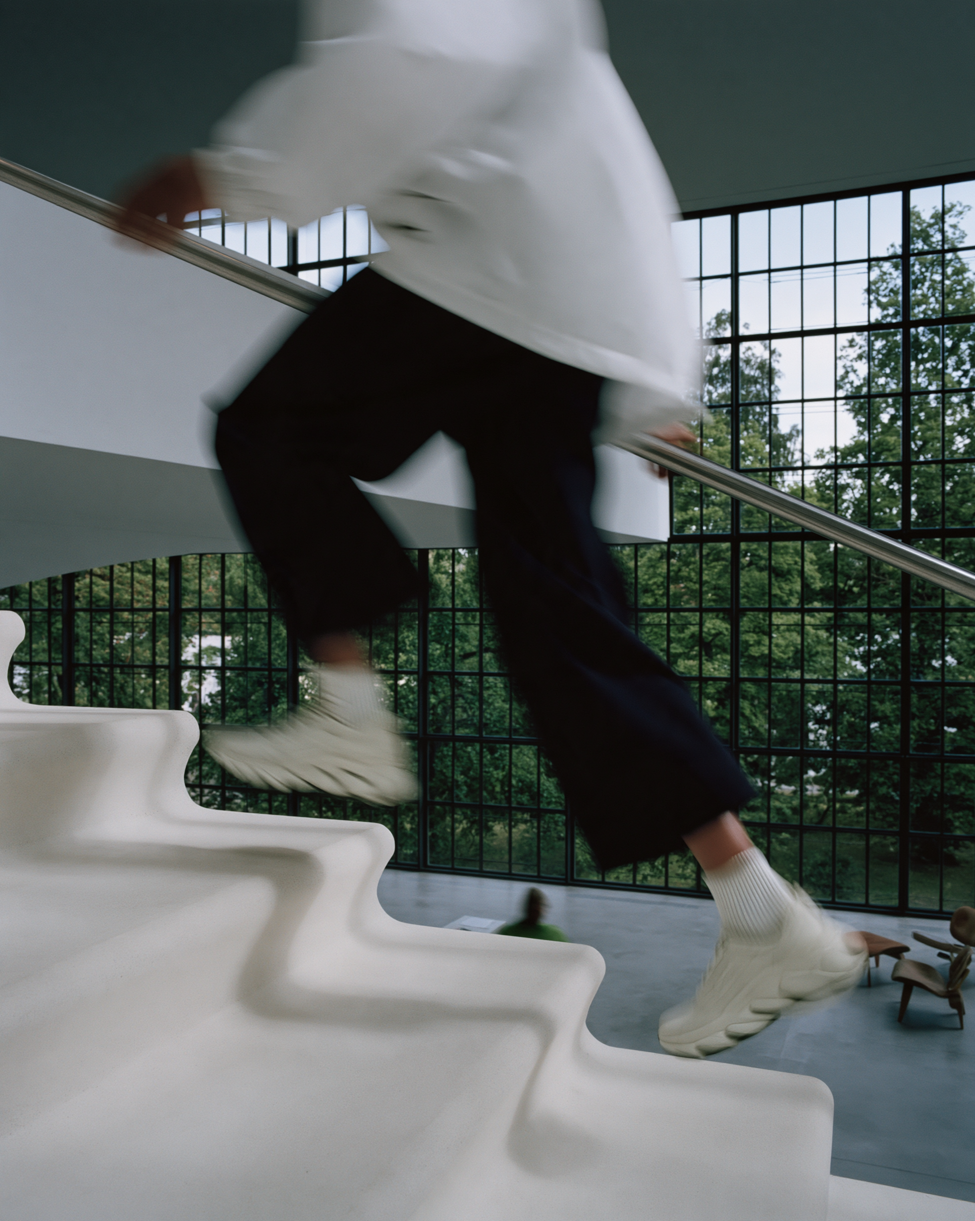 A person moving up a sculptural white staircase in a modern interior